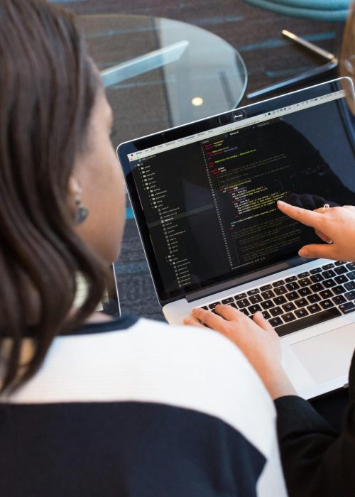 Woman coding on a laptop with programming interface on screen